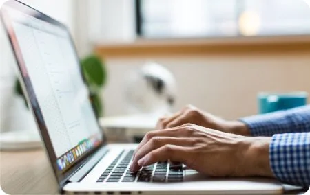 Manos escribiendo en el teclado de una computadora portátil.